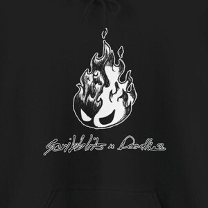 May include: Black hoodie with a white graphic of a flame with a face, and the text "Scribblits n Doodles" in a handwritten style. The design is centered on the front of the hoodie.