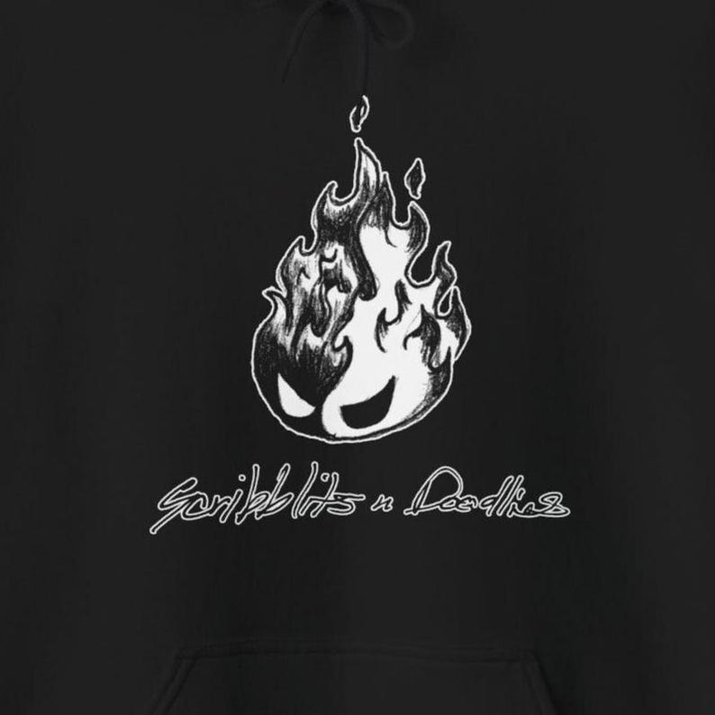 May include: Black hoodie with a white graphic of a flame with a face, and the text "Scribblits n Doodles" in a handwritten style. The design is centered on the front of the hoodie.