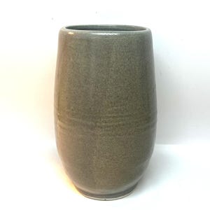 Puede incluir: Un jarr&oacute;n de cer&aacute;mica gris con un cuerpo redondeado y una parte superior ligeramente ensanchada. El jarr&oacute;n tiene una textura moteada y un acabado liso y brillante. El jarr&oacute;n mide unos 20 cm de alto.