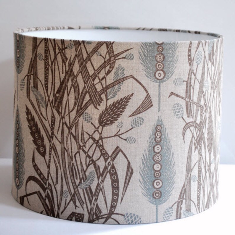 Meadow's Edge Drum Lampshade made by Revill,Revill. An attractive all over pattern of intertwined leaves interspersed by vertical contrast colour larger leaves. Designed by Angie Lewin.  Available in multiple sizes.