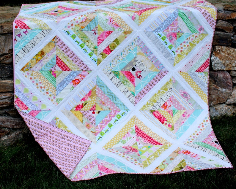 May include: A colorful patchwork quilt with a variety of patterned fabrics in pink, yellow, green, and blue. The quilt features a diamond pattern with white borders and a pink backing. The quilt is made of various fabrics.