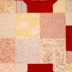 May include: A red, white, and yellow patchwork quilt with various patterns, including floral, geometric, and abstract designs.