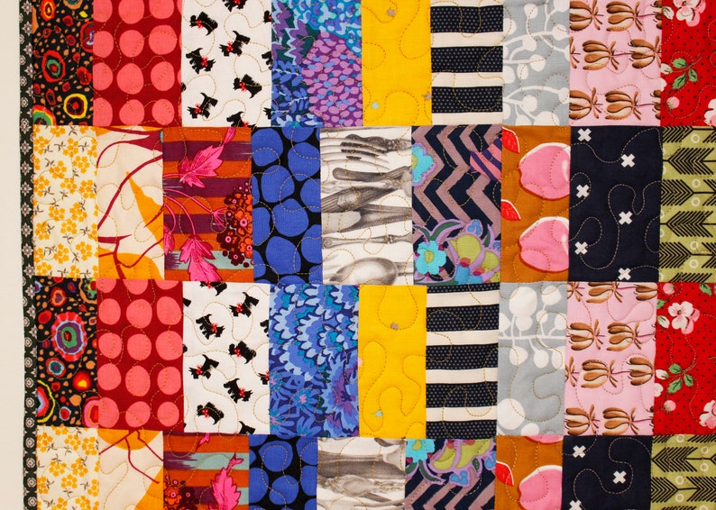 May include: A colorful patchwork quilt with various patterns, including polka dots, stripes, floral designs, and geometric shapes. The quilt is made up of different colored fabrics, including red, pink, blue, yellow, green, and brown.