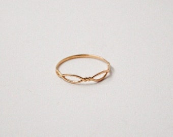 May include: A delicate gold ring with a simple, intertwined design.