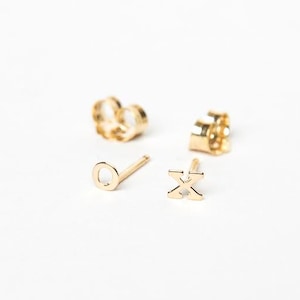 May include: A pair of gold earrings, one with a circle design and the other with an 'X' design.