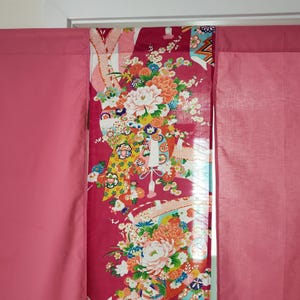 May include: A set of curtains featuring two solid pink side panels and a central panel with a vibrant magenta background. The central panel displays a detailed floral pattern with white, orange, and yellow blossoms, green leaves, and geometric accents.