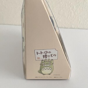 May include: A beige cardboard box with a clear plastic top. The box features a cartoon illustration of Totoro and Japanese text. The box is a gift item.