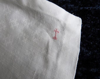 Könnte beinhalten: Ein weißes Leinen-Tuch mit einem kleinen roten gestickten Kreuz in der Ecke.