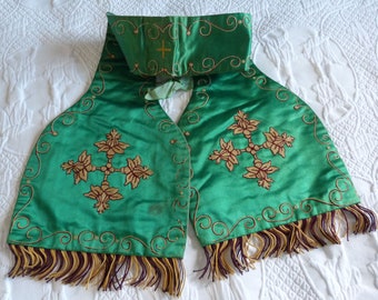 May include: A green satin stole with gold embroidery of a cross and floral designs. The stole has a fringe trim in brown and gold.