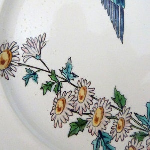 Pode incluir: Um prato de cer&acirc;mica branco com um desenho floral azul e verde. As flores s&atilde;o cor-de-rosa e amarelas com folhas verdes. O prato tem um fundo branco.