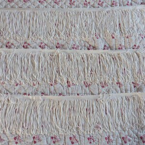 May include: Three rows of white fringe trim, each row is about 1 inch wide. The fringe is made of a soft, white yarn and is perfect for adding a touch of elegance to any project.