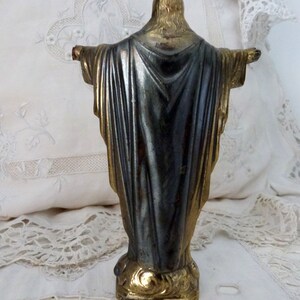 Op de afbeelding: Een klein, goud geverfd metalen beeld van Jezus Christus met uitgestrekte armen. Het beeld staat op een voet met de inscriptie "Breiner, C. France".