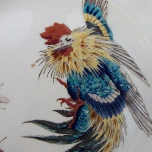 May include: A detailed painting of a rooster with blue, yellow, and red feathers. The rooster is perched on a branch with a bee flying nearby.