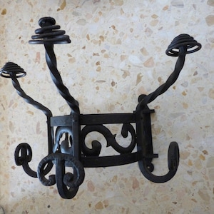 May include: A black wrought iron coat rack with a decorative scroll design and multiple hooks.
