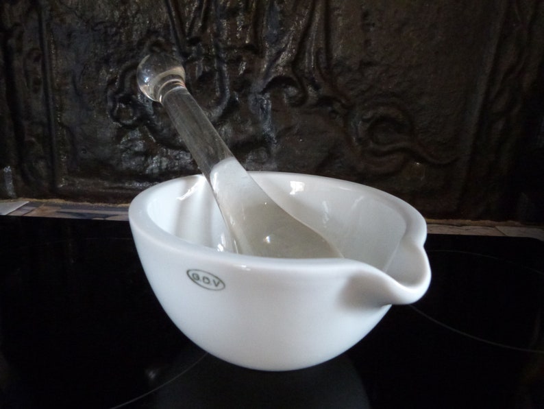May include: White porcelain mortar and pestle set with a glass pestle. The mortar has a small spout and the brand name "GOV" is printed on the bottom.