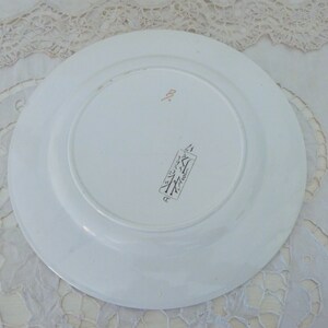 Pode incluir: Prato de cer&acirc;mica branco com borda dourada e uma pequena marca dourada na parte inferior. A marca inclui o texto "Made in Japan" e um s&iacute;mbolo de &aacute;rvore.