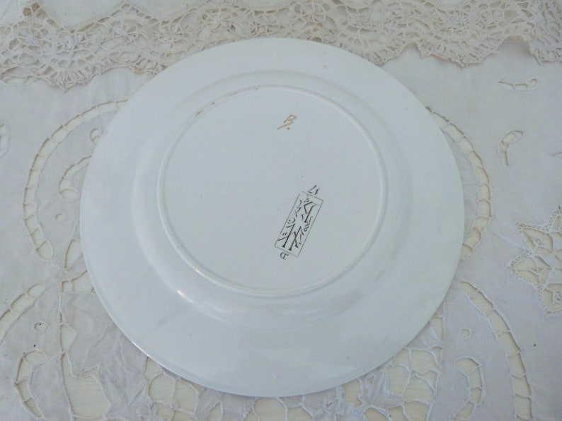 Pode incluir: Prato de cer&acirc;mica branco com borda dourada e uma pequena marca dourada na parte inferior. A marca inclui o texto "Made in Japan" e um s&iacute;mbolo de &aacute;rvore.