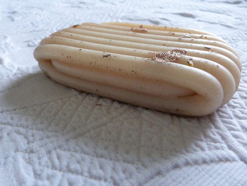 May include: A close-up of a white, ribbed bar of soap with brown spots and flecks of gold glitter.
