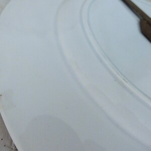 May include: White ceramic plate with a brown stain on the edge.