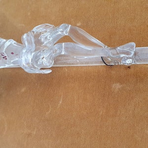 May include: A clear glass crucifix with a depiction of Jesus Christ. The figure is detailed with red paint to represent blood.