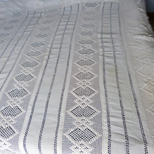 May include: White crocheted bedspread with a diamond pattern and a lace border.