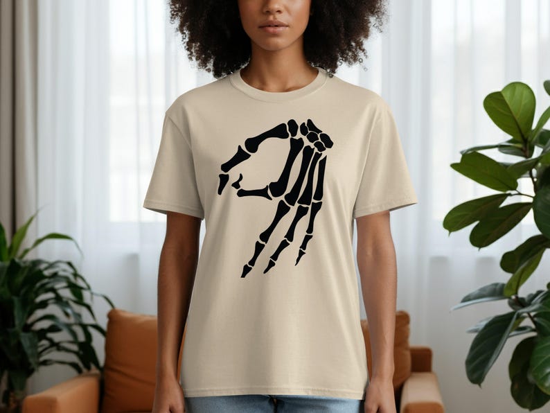 Tan t-shirt with black skeleton hand making the 'okay' gesture.