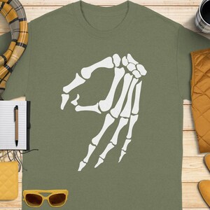 Olive green t-shirt with white "okay" hand gesture graphic.
