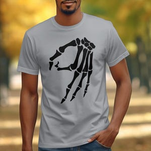Skeleton hand making the "okay" gesture on a grey t-shirt.