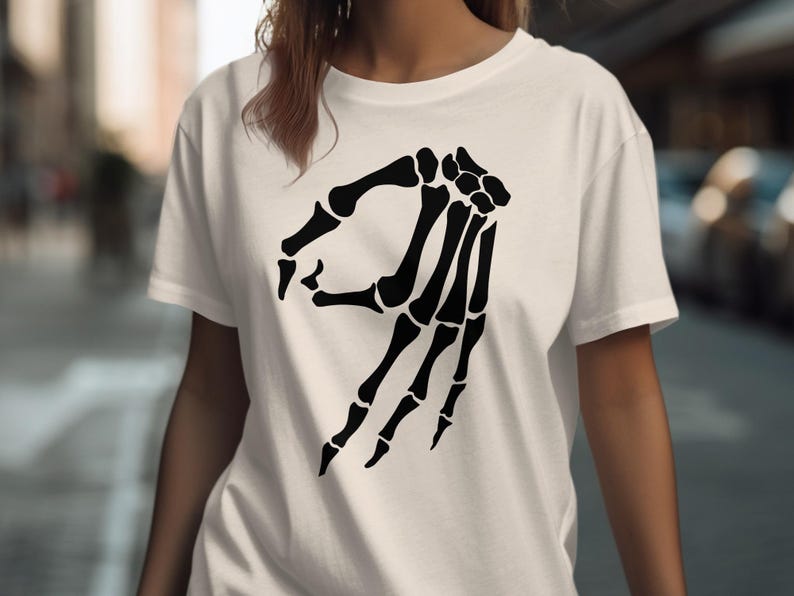 White t-shirt with black skeleton hand making the "okay" gesture.