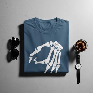 Blue t-shirt with white skeleton hand pointing left, sunglasses and watch.