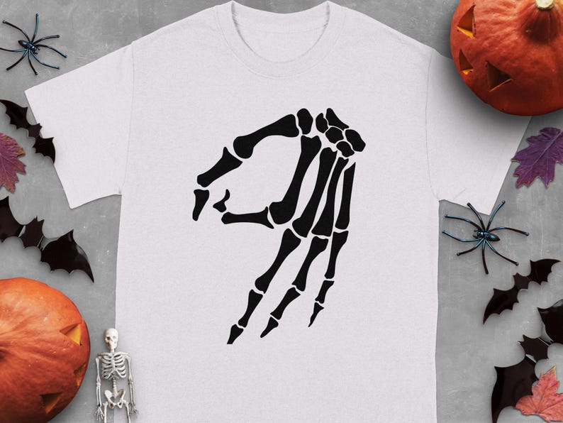 Skeleton hand making the "circle game" gesture on a white t-shirt.