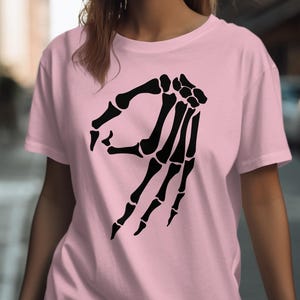 Pink t-shirt with a black skeleton hand making the "okay" gesture.