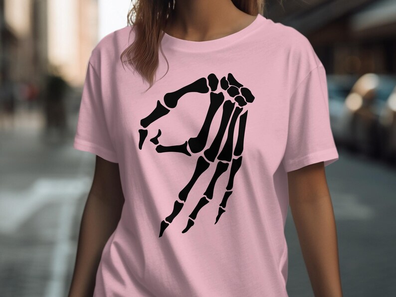 Pink t-shirt with a black skeleton hand making the "okay" gesture.