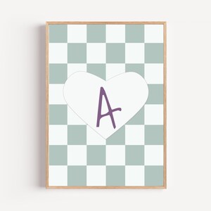 Könnte beinhalten: Gerahmtes Kunstwerk mit einem hellen Holzrahmen. Das Kunstwerk hat ein Schachbrettmuster in Grün- und Weißtönen. Eine weiße Herzform mit dem lila Buchstaben "A" ist auf dem Kunstwerk zentriert.