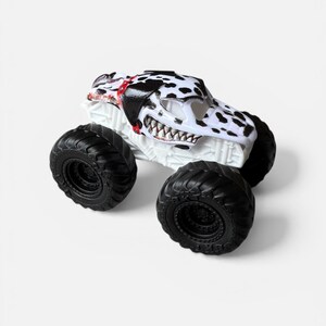 K&ouml;nnte beinhalten: Ein wei&szlig;es Monstertruck-Spielzeug mit schwarz-wei&szlig;en Dalmatiner-Punkten auf der Kabine. Der Truck hat gro&szlig;e schwarze Reifen und einen detaillierten, zahnartigen K&uuml;hlergrill. Die Kabine hat rote Akzente.