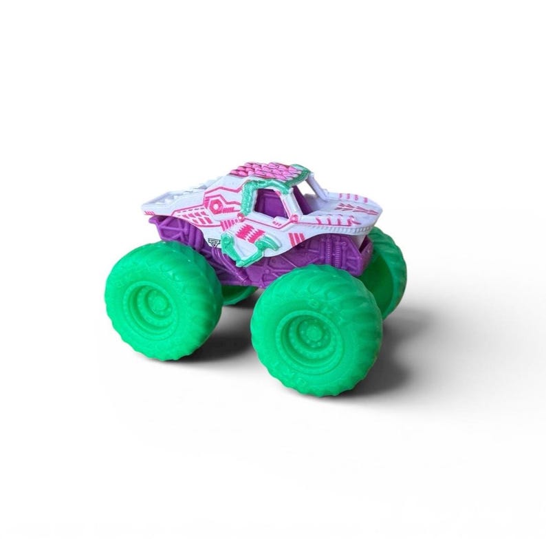 K&ouml;nnte beinhalten: Ein Spielzeug-Monstertruck mit wei&szlig;er Karosserie, lila Fahrgestell und gr&uuml;nen R&auml;dern. Der Truck-K&ouml;rper hat rosa und gr&uuml;ne Akzente. Die gro&szlig;en gr&uuml;nen Reifen sind f&uuml;r das Gel&auml;nde geeignet.