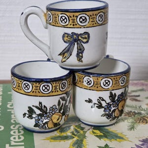 May include: A set of three ceramic mugs with a speckled, matte finish. The mugs are in shades of cream, light gray, and dark gray. Each mug has a simple, minimalist design, perfect for coffee or tea.