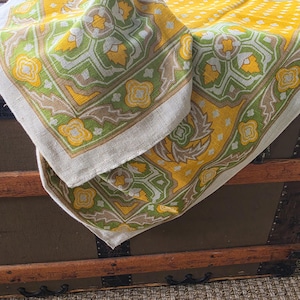 May include: A woven textile featuring a repeating geometric pattern in shades of mustard yellow, olive green, and beige. The fabric displays a central motif of stylized floral shapes surrounded by intricate borders, with a textured, off-white base.