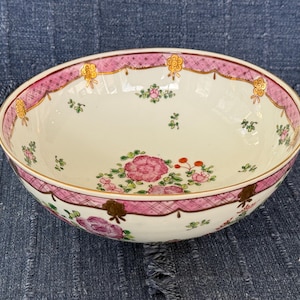 May include: Oval ceramic serving bowl with a white interior and a pink and gold decorative border. The bowl features floral and botanical designs in pink, green, and gold.