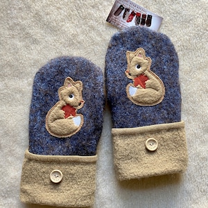 May include: A pair of blue and tan wool mittens with a fox embroidered on each. The mittens have a button on the cuff. The mittens are made by Nordic Star Studio.
