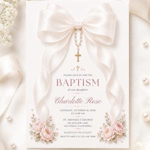 Puede incluir: Una tarjeta de invitación de bautizo blanca con un gran lazo de satén crema en la parte superior y un dije de rosario colgante. El texto dice: Please join us for the baptism of our daughter Charlotte Rose, Saturday, October 10, 2026, at 11:00 AM.