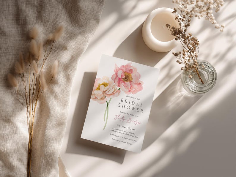 Pu&ograve; includere: Un invito per un addio al nubilato con peonie rosa e gialle ad acquerello. L'invito include il testo "Bridal Shower" e i dettagli dell'evento. Sono presenti anche un piccolo vaso di vetro con fiori secchi, una candela bianca e fiori secchi decorativi.