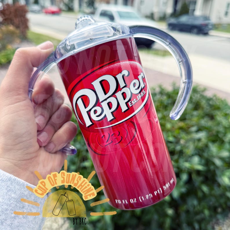 May include: A red and white Dr. Pepper-themed tumbler with a clear handle and lid. The tumbler features the Dr. Pepper logo and the text "Est.1885". It holds 20 fl oz (1.25 PT) or 591 ml.