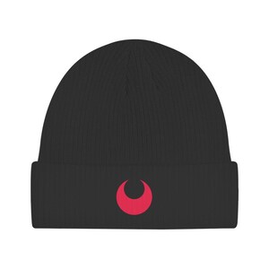 May include: A black ribbed knit beanie featuring a cuffed brim and a centered, solid red crescent moon graphic. The hat is constructed from a textured fabric with vertical lines running from the crown to the base of the folded cuff.