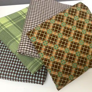 May include: Four folded fabric squares with various plaid and gingham patterns. The colors include shades of green, brown, and blue. One fabric has a brown and turquoise gingham pattern. Another has a brown and white gingham pattern. The other two have plaid patterns.