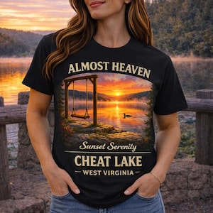 May include: Black t-shirt with the text "Almost Heaven" above a scenic sunset image with a swing set over a lake. The text "Sunset Serenity Cheat Lake - West Virginia" is below the image.
