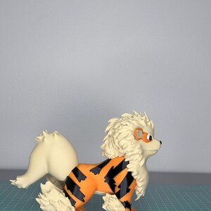 May include: A detailed figurine of a canine creature with orange and black markings, cream-colored fur, and a fluffy mane. The figurine has a determined expression and is posed in a standing position. The overall design is reminiscent of a popular animated character.