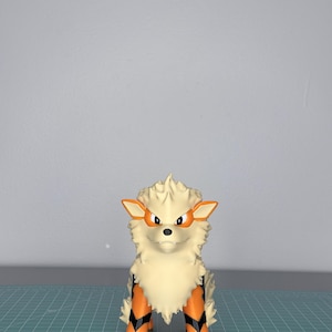 May include: A cream-colored, stylized Arcanine figure with orange and black accents. The figure has a fluffy mane, orange ears, and orange and black markings on its legs. It stands on a green cutting mat.