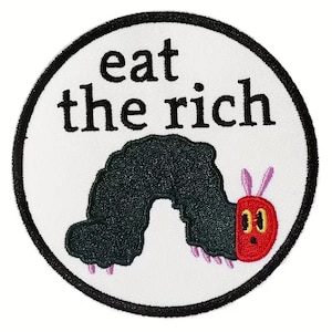 May include: Embroidered patch with the words "eat the rich" in black, above a cartoon caterpillar. The caterpillar is dark green with a red head, pink feet, and pink antennae. The patch is circular with a black border.