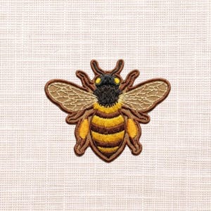 May include: Embroidered bee patch with a detailed design. The bee features a black head, yellow eyes, and a body with yellow and brown stripes. The wings are a light brown color, and the patch is outlined in brown.